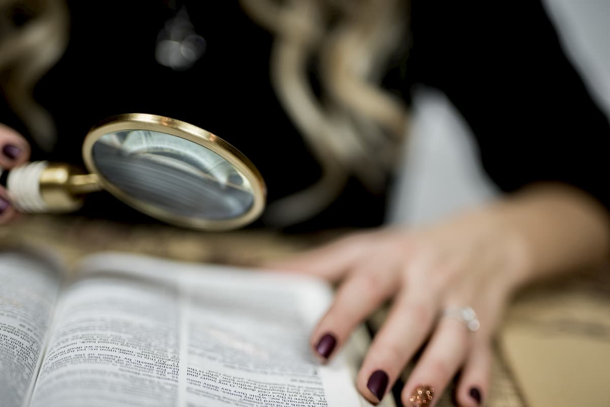 虫眼鏡を使って本を読む女性